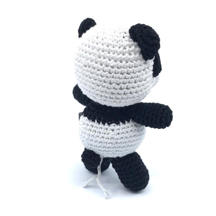 Crochet panda toy sitting, white body with black ears and arms, textured crochet feet.