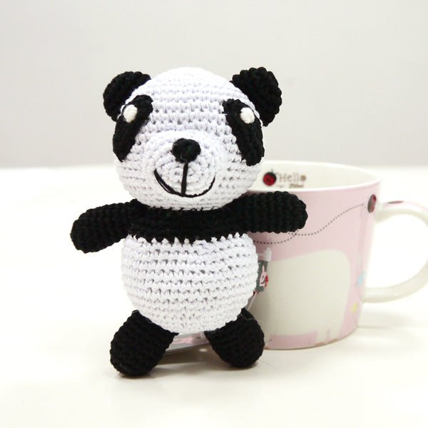 Crochet panda toy standing, black-and-white face with round eyes and long black arms.