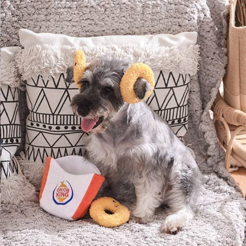 Onion King plush pouch and tan ring toy with a gray dog on a soft bed