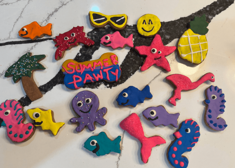 Assorted dog cookies with colorful fish, stars, and seahorses on a tray