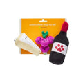 Three plush dog toys: cream bone, purple critter with green antlers, black paw bottle