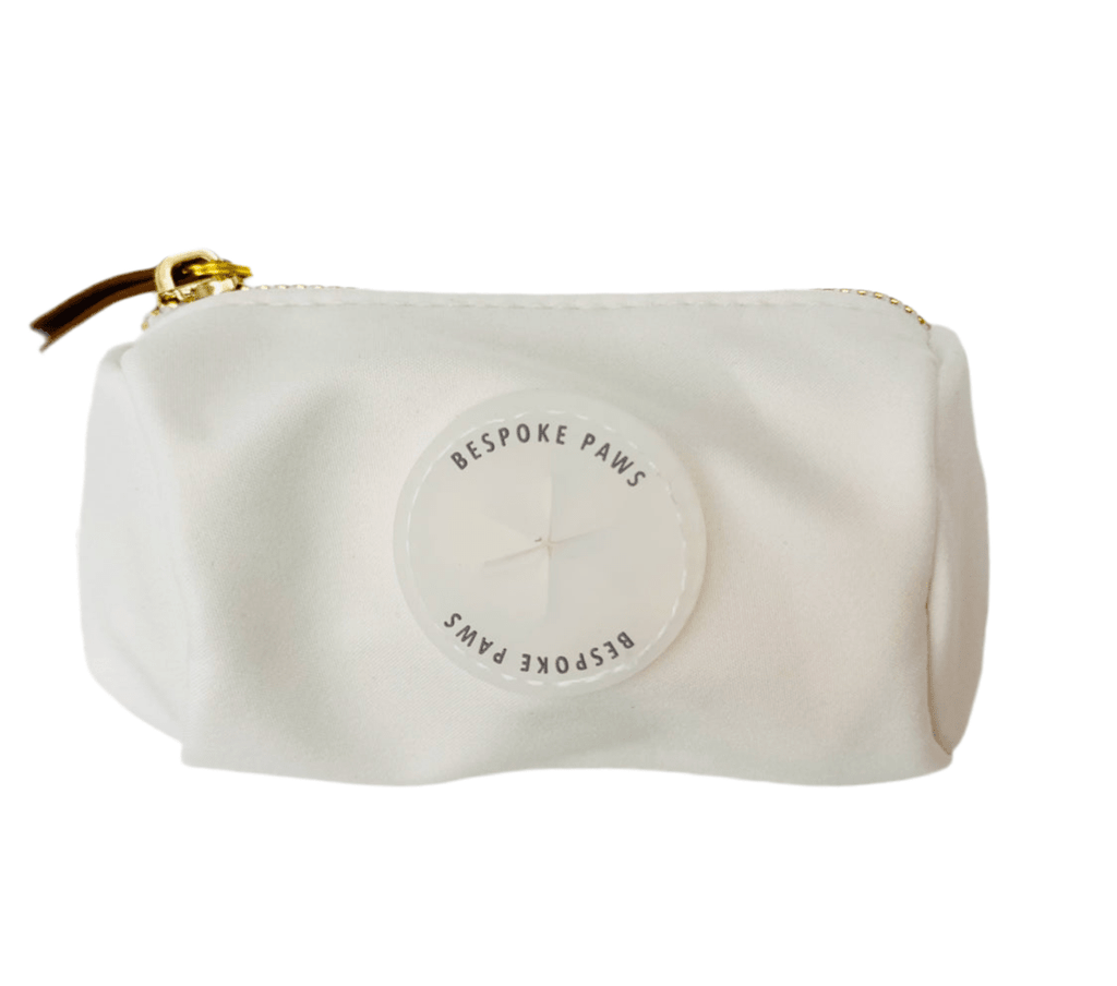 Ivory waste bag dispenser pouch with gold zipper, front logo patch, and loop strap