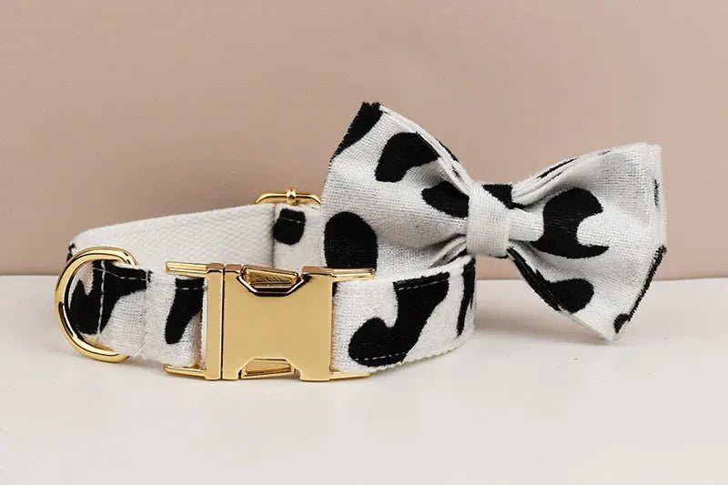 Black-and-white cow print dog collar with large bow tie and gold buckle hardware