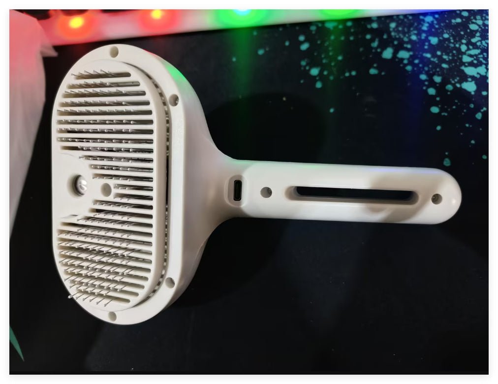 Close-up of white pet dematting comb brush head with metal teeth and mist vent