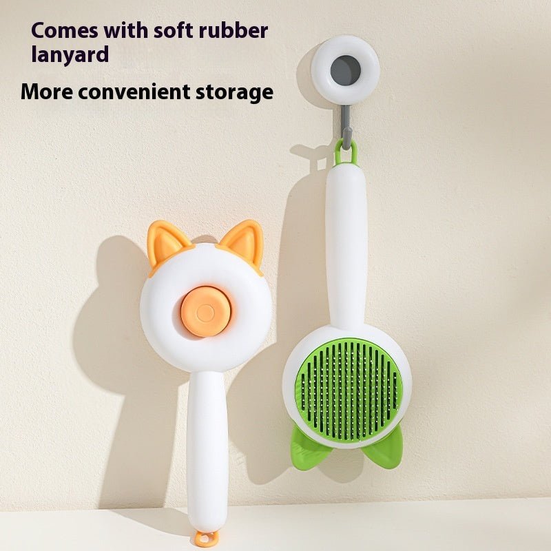 Self-cleaning pet hair grooming brush with orange cat-ear head, green bristle pad, storage lanyard