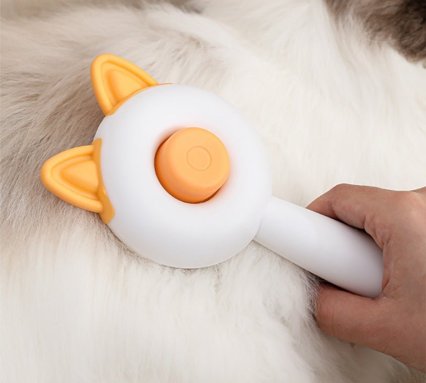 Self-cleaning pet grooming brush with orange cat-ear head and cleaning button on cat fur