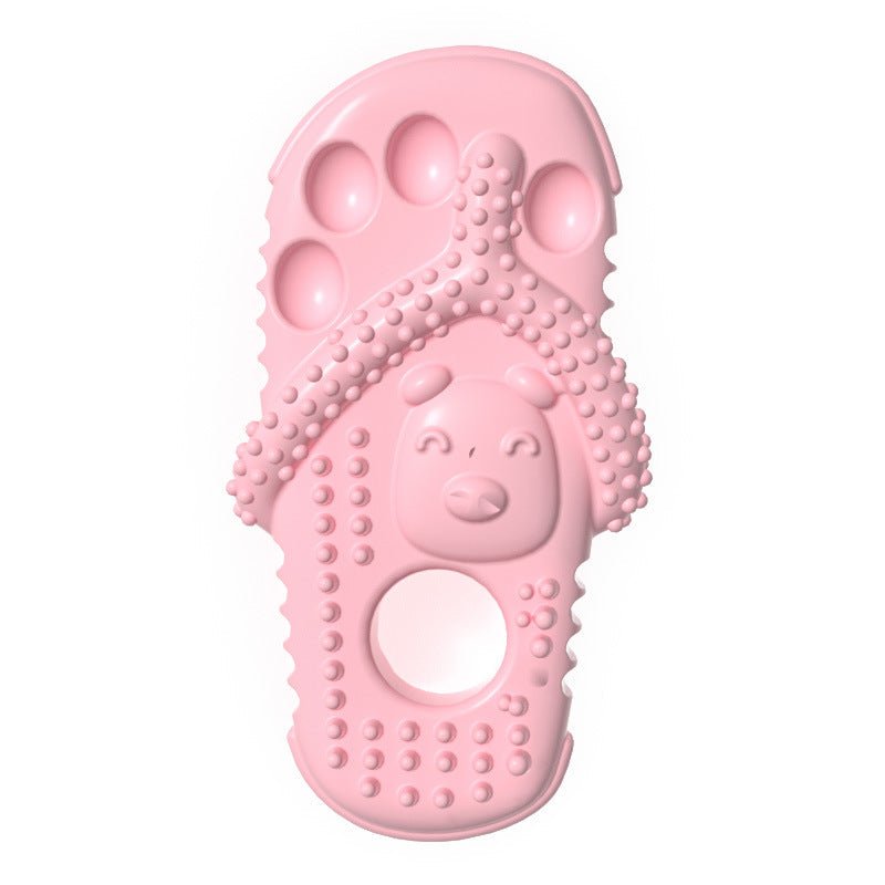 Pink rubber slipper-shaped dog chewing toy with face design, nubs, and hole
