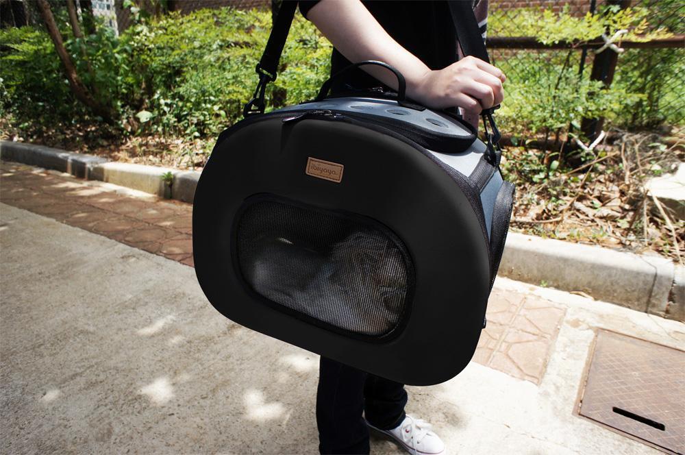 Black hard-shell pet dog carrier with front oval mesh window and top handle