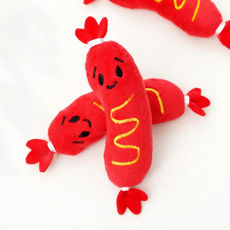 Close-up of red plush hot dog-shaped dog toy with stitched face and yellow wavy details