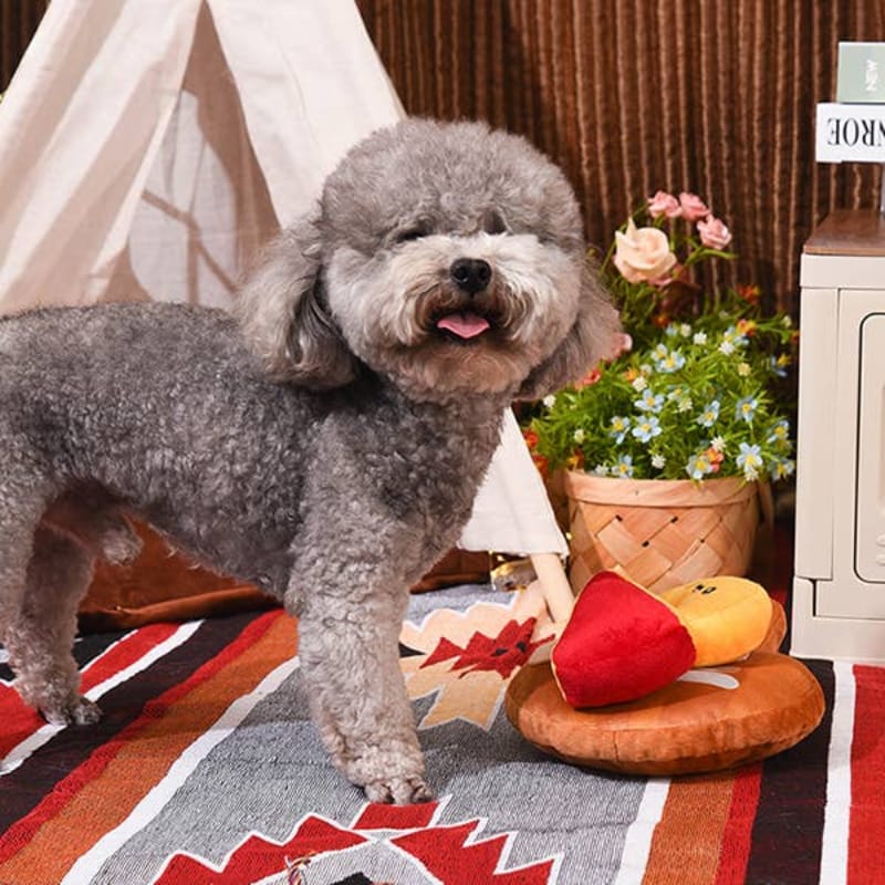 Plush cheese board interactive toy in use with gray dog standing beside it