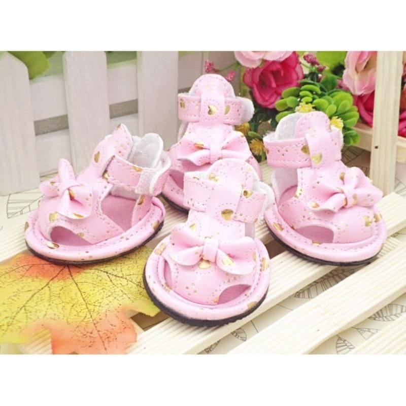 Four pink dog sandals with bow accents and adjustable straps, gold eyelets, set of 4