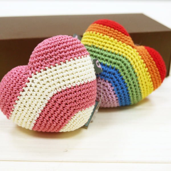 Two crocheted rainbow heart toys with multicolor stripe patterns and fabric tags