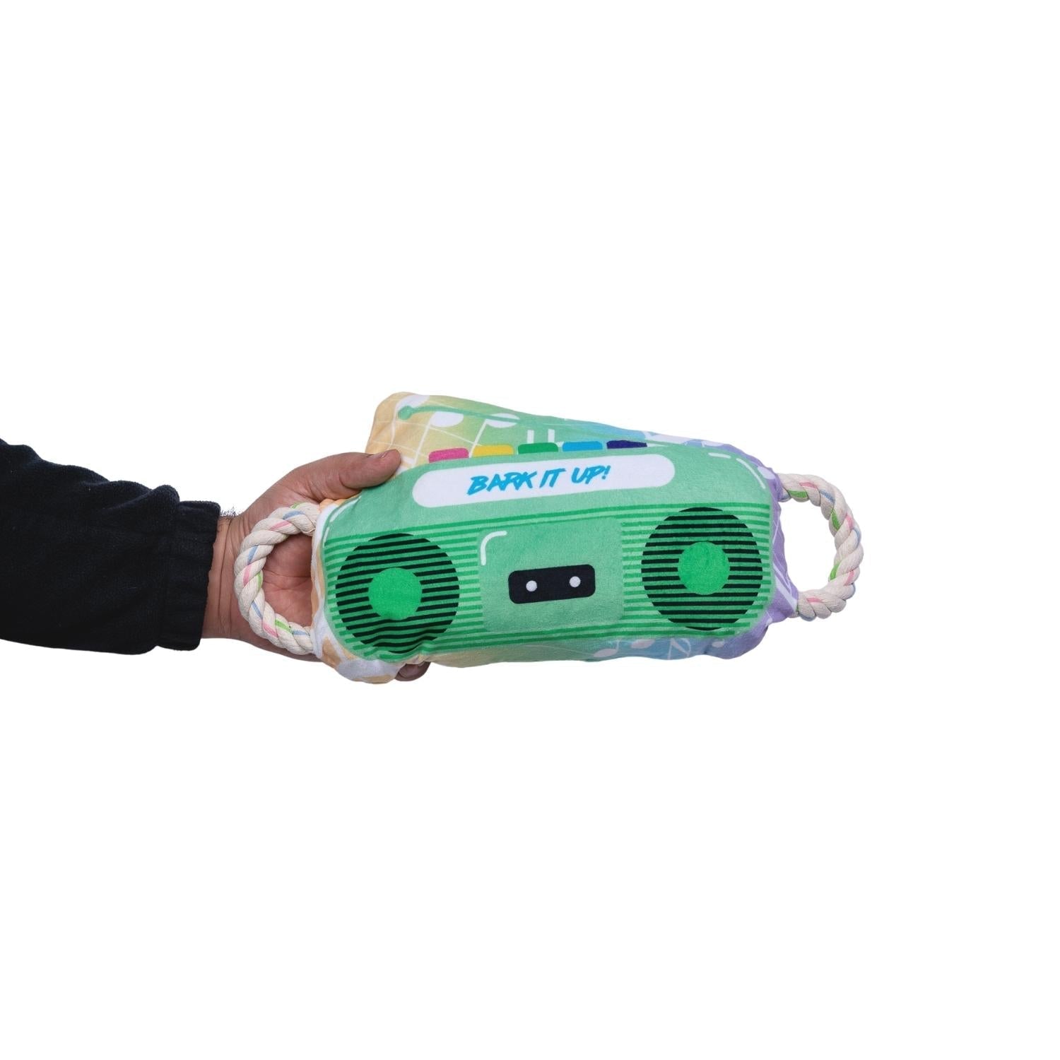 Green boombox plush dog toy with rope handles, held in a hand