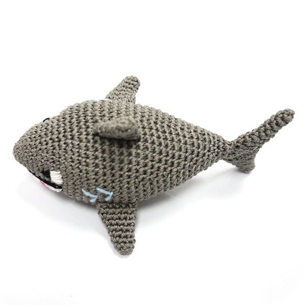 Gray crocheted shark toy with raised dorsal fin and curved tail, side profile