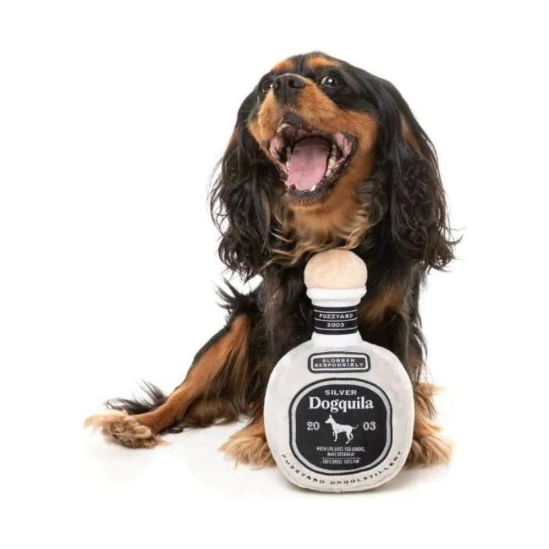 Bottle-shaped plush dog toy with squeaker, shown with a panting dog