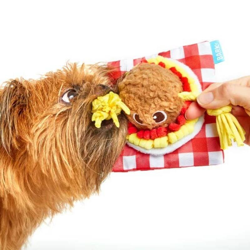 Brown meatball plush dog toy with yellow rope spaghetti and red check gingham, held by hand