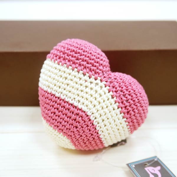 Pink and cream striped crochet heart toy with textured stitches, angled view