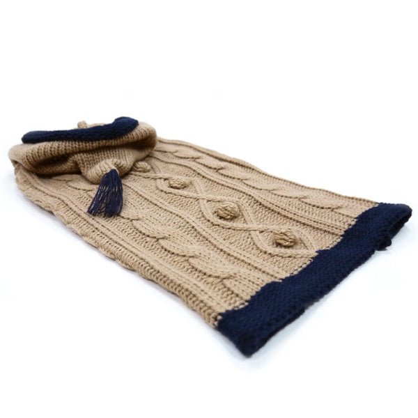 Beige knit hooded dog sweater laid flat, navy trim and short tassel on back