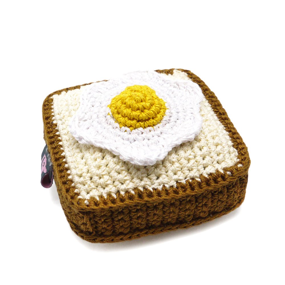 Crochet toast toy, off-white base with yellow yolk and white egg, brown edging