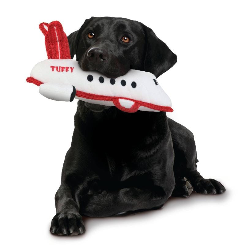 Durable dog airplane plush toy in white and red, shown with a black dog lying