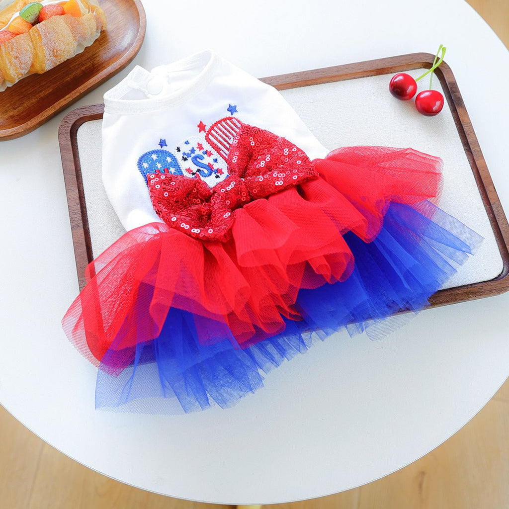 Dog tutu dress laid flat: white top with red sequined bow and red-blue tulle skirt