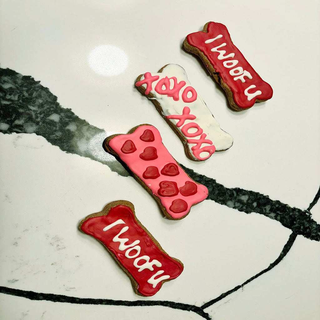 Dog bone cookies with red, white, and dark paw-print and Woof designs