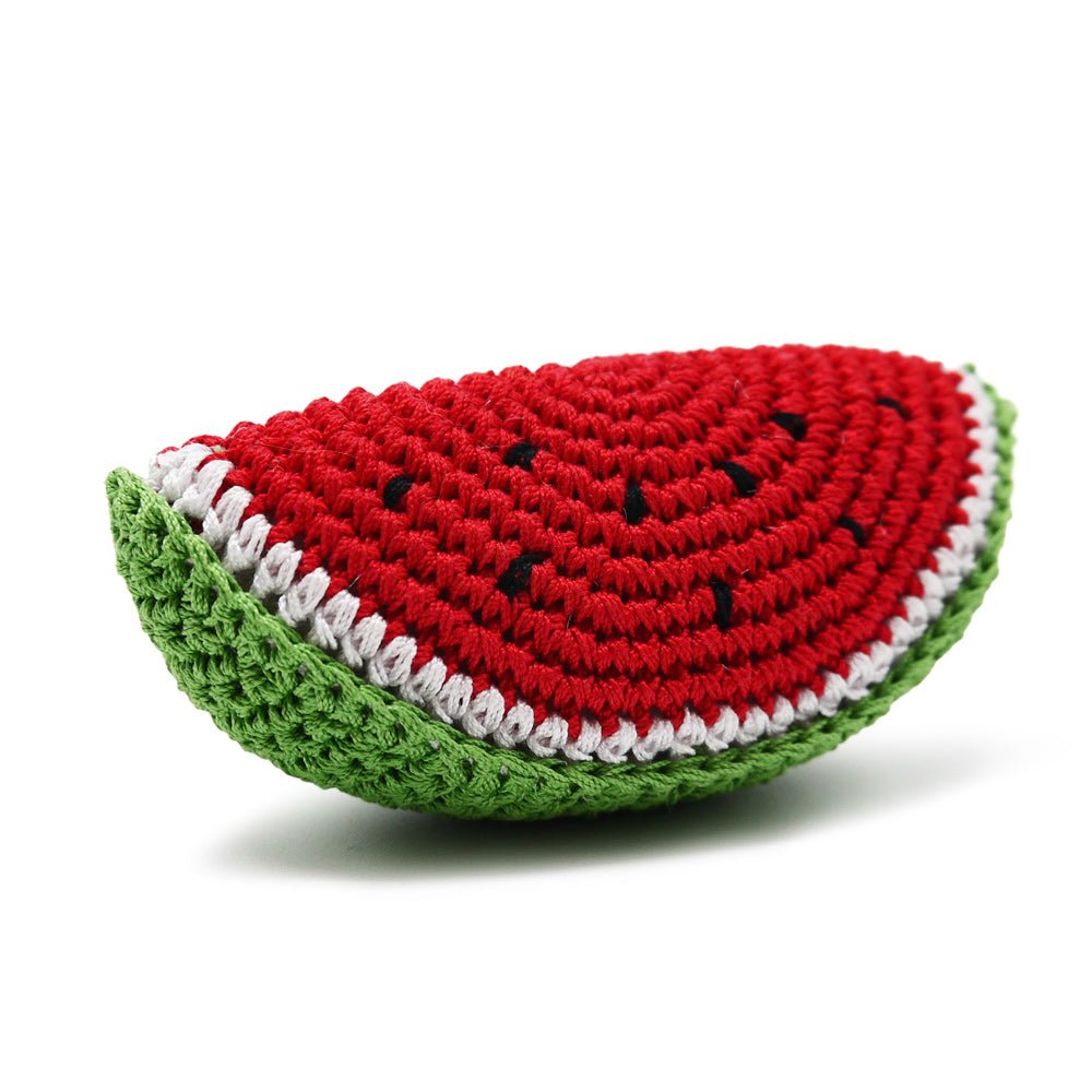 Crochet watermelon toy slice, angled view: red surface, green edge, white border