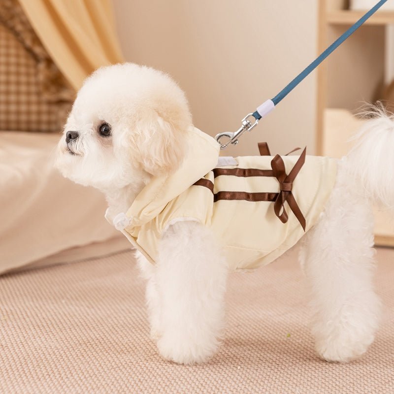 Small dog wearing cream fleece vest with bow tie and hood, on leash