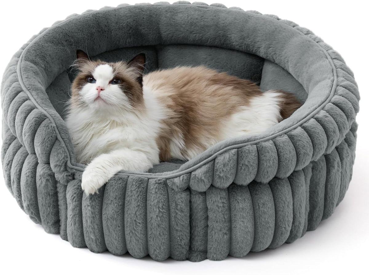 Warm gray round plush pet bed with cushioned rim; calico cat resting inside.
