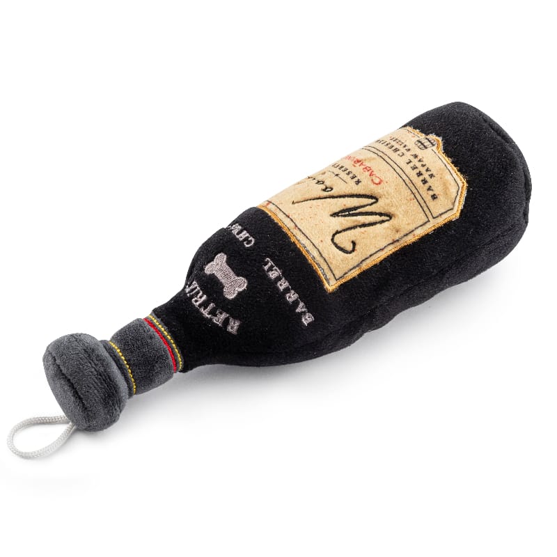 Black plush bottle dog toy with beige label, bone icons, and dangling pull cord