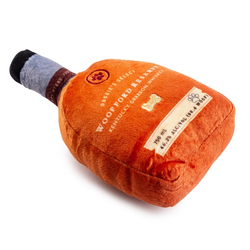 Plush squeaky dog toy bottle in orange with gray cap, angled view of label details